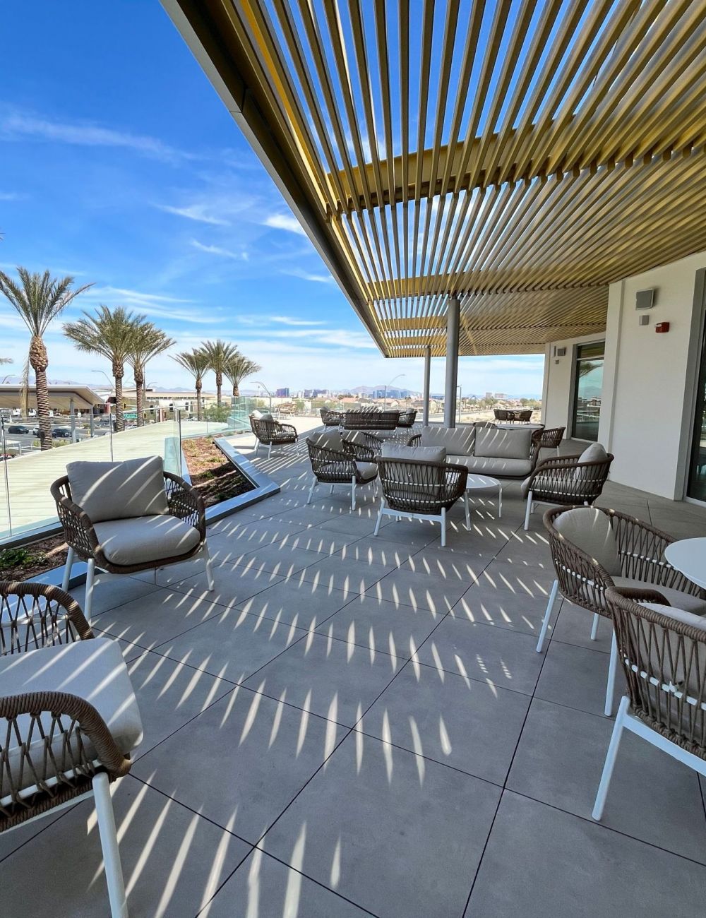 Evora: A serene patio at the new resort featuring elegant seating and lush palm trees, perfect for relaxation and leisure.